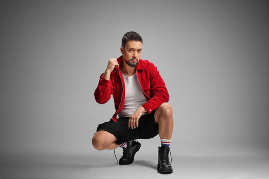 Stylish man in a red jacker kneeling and posing