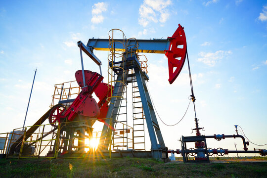 Pumpjack in oil well of oil field on sunset in Industrial crude area. Crude pump jack working on oil field. Pumpjack, Oil drill rig, drilling derrick in oilfield. Natural gas, Crude petroleum industry