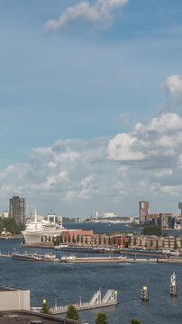 Aerial timelapse view over Maashaven with moored inland ships, Katendrecht and Maas River in the background. Dramatic cloudy sky over skyscrapers with warm morning light. Cargo port on a background
