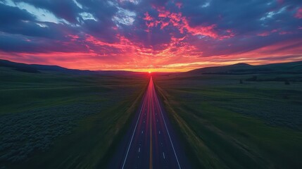 Highway stretching into distant green mountains, dramatic sunset sky