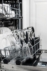 Dishwasher interior showcasing clean glassware and plates in a modern kitchen setting, emphasizing efficient cleaning technology and organized dish storage with copy space