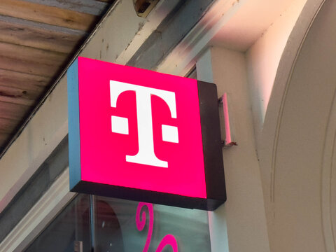 Zagreb, Croatia - December 14, 2025: T-Mobile store sign illuminated in vibrant pink color, showcasing the iconic logo against a modern urban backdrop with copy space