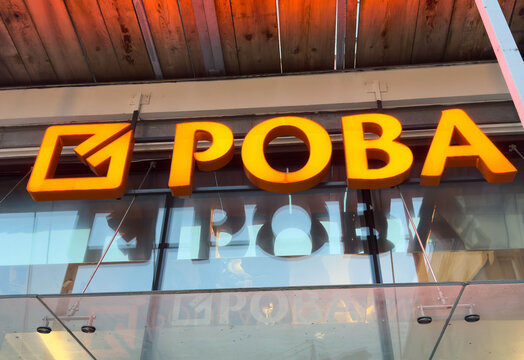 Zagreb, Croatia - December 14, 2025: ROVA brand signage illuminated in bright orange against a glass storefront, showcasing modern design and urban atmosphere with copy space