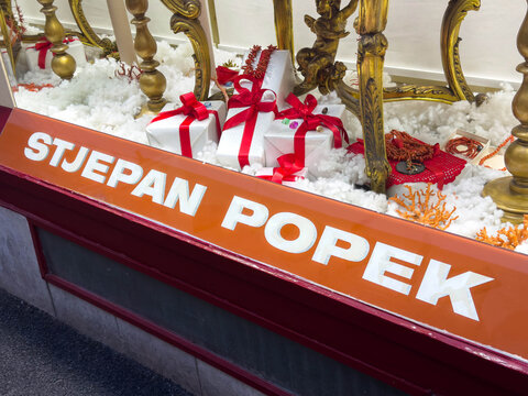 Zagreb, Croatia - December 14, 2025: Stjepan Popek storefront display featuring festive decorations, white snow-like material, and beautifully wrapped gifts creating a holiday atmosphere