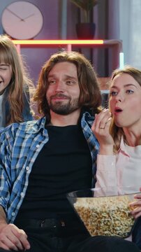 Adorable joyful carefree friendly loving family having fun together at home in the evening when previsioning interesting program on TV set simultaneously tasting popcorn
