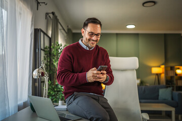 Smiling man working from home checking mobile phone
