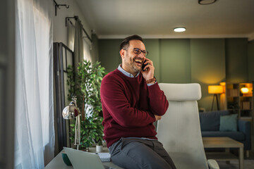 Man laughing while talking on phone working from home