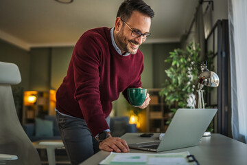 Man working on laptop at standing desk at home