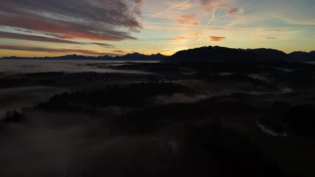 Foggy Ammer valley glowing under pre-dawn pastel sky, alpine silhouettes and rolling mist creating serene winter mood, ideal for tourism campaigns.