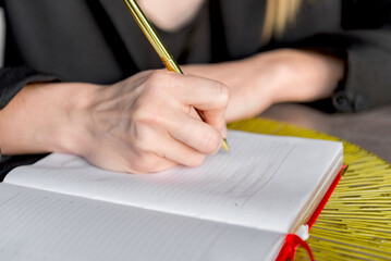 Close-up of a hands holding a pen and a notebook.