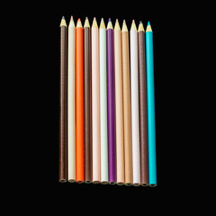 Assortment of artist's colorful pencils laid in a row isolated on black background