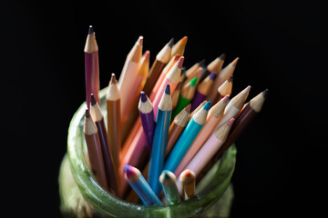 Assortment of artist's colorful pencils isolated on black background.  Shallow depth of field.