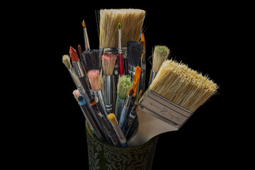 Set of various sized paintbrushes isolated on black background.
