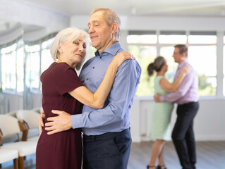 Obraz premium Couple of elderly man and elderly woman dancing waltz in studio