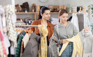 Two young women buying winter and autumn outerwear in clothing store