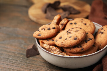 Yummy chocolate chip cookies in bowl on wooden table, closeup. Space for text