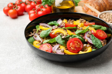 Tasty salad with lentils and vegetables on grey table, closeup
