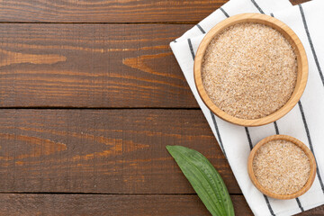 Psyllium husk powder with fresh leaves on wooden background, top view © Liami