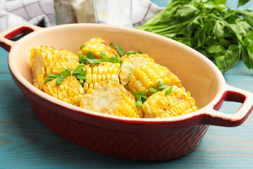 Pieces of grilled corn cobs with green onions on blue wooden table, closeup