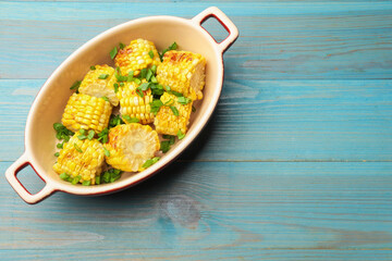 Pieces of grilled corn cobs with green onions on blue wooden table, top view. Space for text