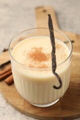 Delicious protein shake in glass, cinnamon and vanilla pods on table, closeup