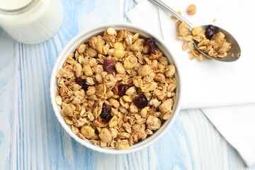 Tasty granola with dried fruits and milk in light blue wooden table, flat lay