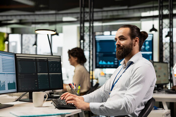 Obraz premium Professional male administrator in modern workspace analyzing forecast insights and business strategy on a computer monitor, ensures report writing and planning for productivity.