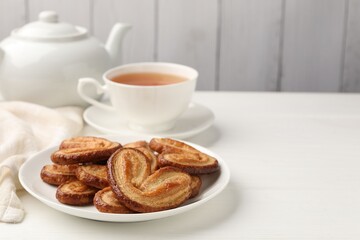 Yummy palmier cookies served with tea on white wooden table, closeup. Space for text