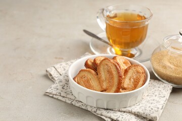 Yummy palmier cookies, tea and brown sugar on light grey table, closeup