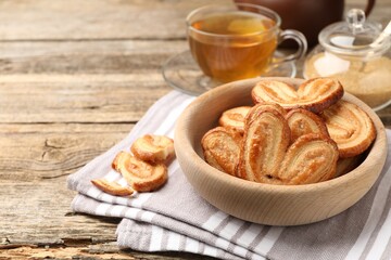Yummy palmiers, tea and brown sugar on wooden table, closeup. Space for text