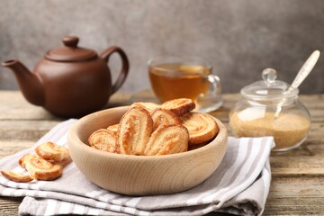 Yummy palmier cookies, tea and brown sugar on wooden table, closeup
