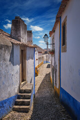 Exploring the narrow streets of Obidos with white houses under blue skies