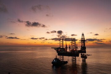 Fototapeta premium Aerial view of offshore jack up rig and offshore platform during sunset for oil and gas exploration and production.