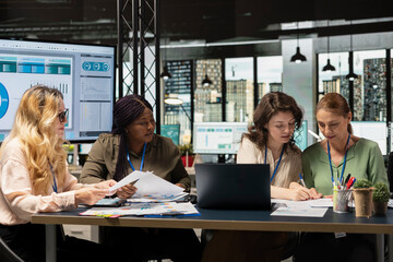 Diverse coworkers team form a powerful startup discuss business strategy, analyzing performance data on laptop and documents aligned around success, progress and shared objectives.
