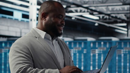 Data center engineer deploying AI driven management tools using laptop. Server farm employee...