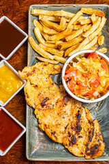 Close Up of Juicy Grilled Chicken Breast Fillet with Sear Marks Served with Fresh Salad and French Fries on Green Plate