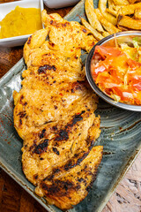 Close Up of Juicy Grilled Chicken Breast Fillet with Sear Marks Served with Fresh Salad and French Fries on Green Plate