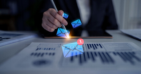 An engaging scene depicting a hand using a pen to interact with digital email notifications and business graphs, illustrating modern communication and analysis in a professional workspace. Gantry