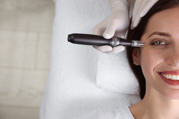 Woman undergoing microneedling procedure in beauty salon, top view. Space for text
