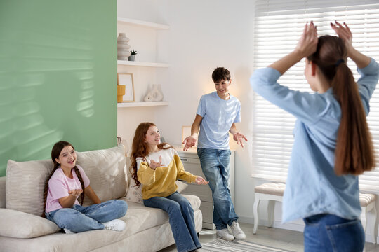 Group of teenagers playing charades game at home