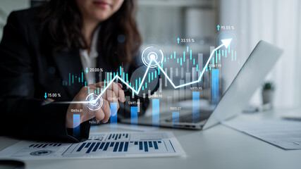 A business professional engages with digital graphs showcasing financial data on a laptop,...