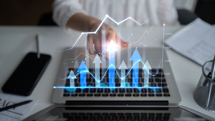 A business professional uses a laptop to analyze digital data graphs showing upward trends. This image depicts financial analysis, growth, and strategic insights. Scalp