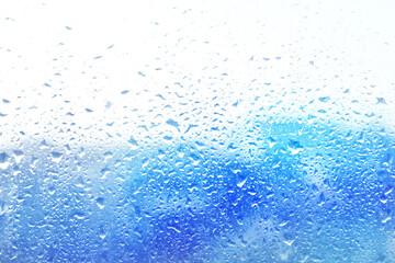 Fototapeta premium Blurred cityscape, view through glass surface with water drops