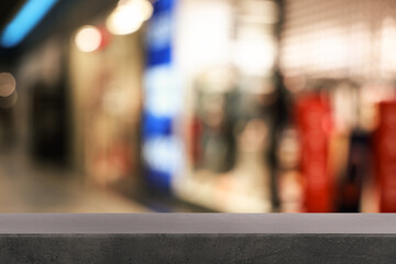 Empty grey table against blurred view of shopping mall. Space for design