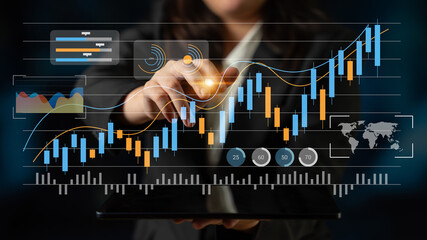 A business professional engages with a digital tablet displaying glowing financial graphs and charts, highlighting trends in market data, perfect for finance and analytics themes. Gantry