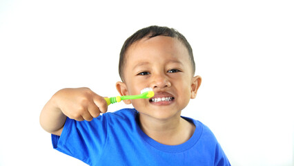 A small Asian boy is carrying a green children's toothbrush, a photo as an education about brushing teeth from an early age, isolated on a white background.