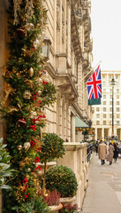 London street displaying festive Christmas decorations, Union Jack flag flying high, people walking...