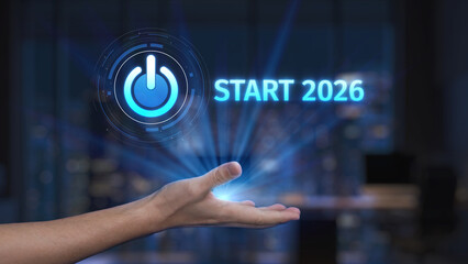 A hand reaching out with a glowing power button symbol above, signifying the beginning of 2026 in a high-tech setting. Ideal for themes of innovation and new beginnings. Synapse