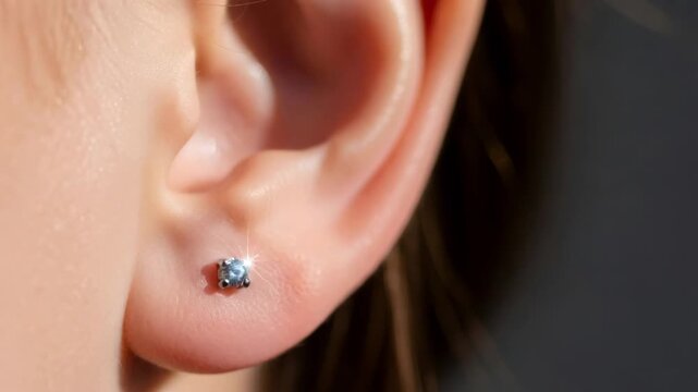 Woman with closed eye and diamond earring on earlobe, a piercing concept for beauty and jewelry style.