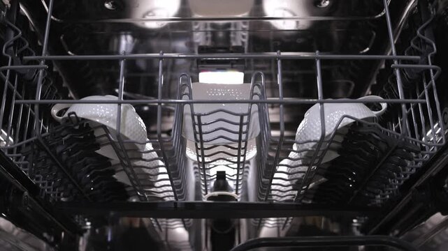 Hand places white dish into dishwasher rack, showcasing organized loading process, highlighting the arrangement of dishes and the interior design of the appliance